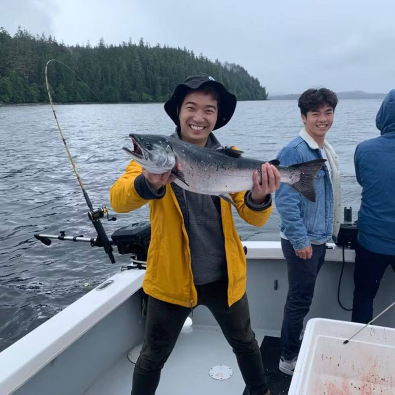 happy guy smiling and posing for a picture on a boat with a fish he caught