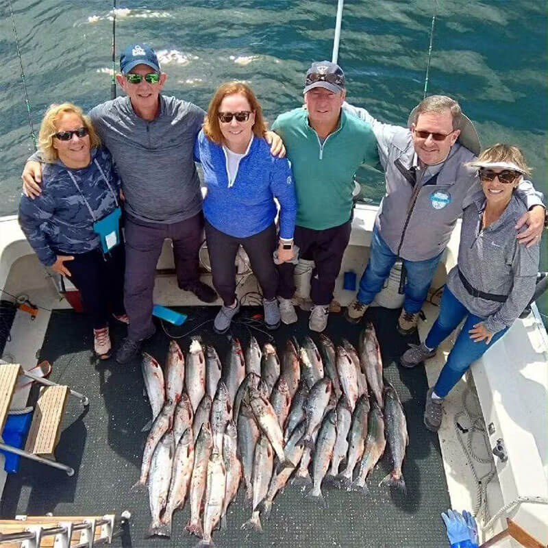 family and friends taking a photo with all the fish they caught on the boat